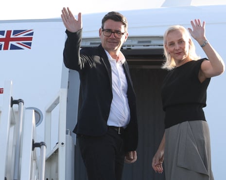 Andy Burnham and his wife, Marie-France van Heel, wave from the doorway of a plane