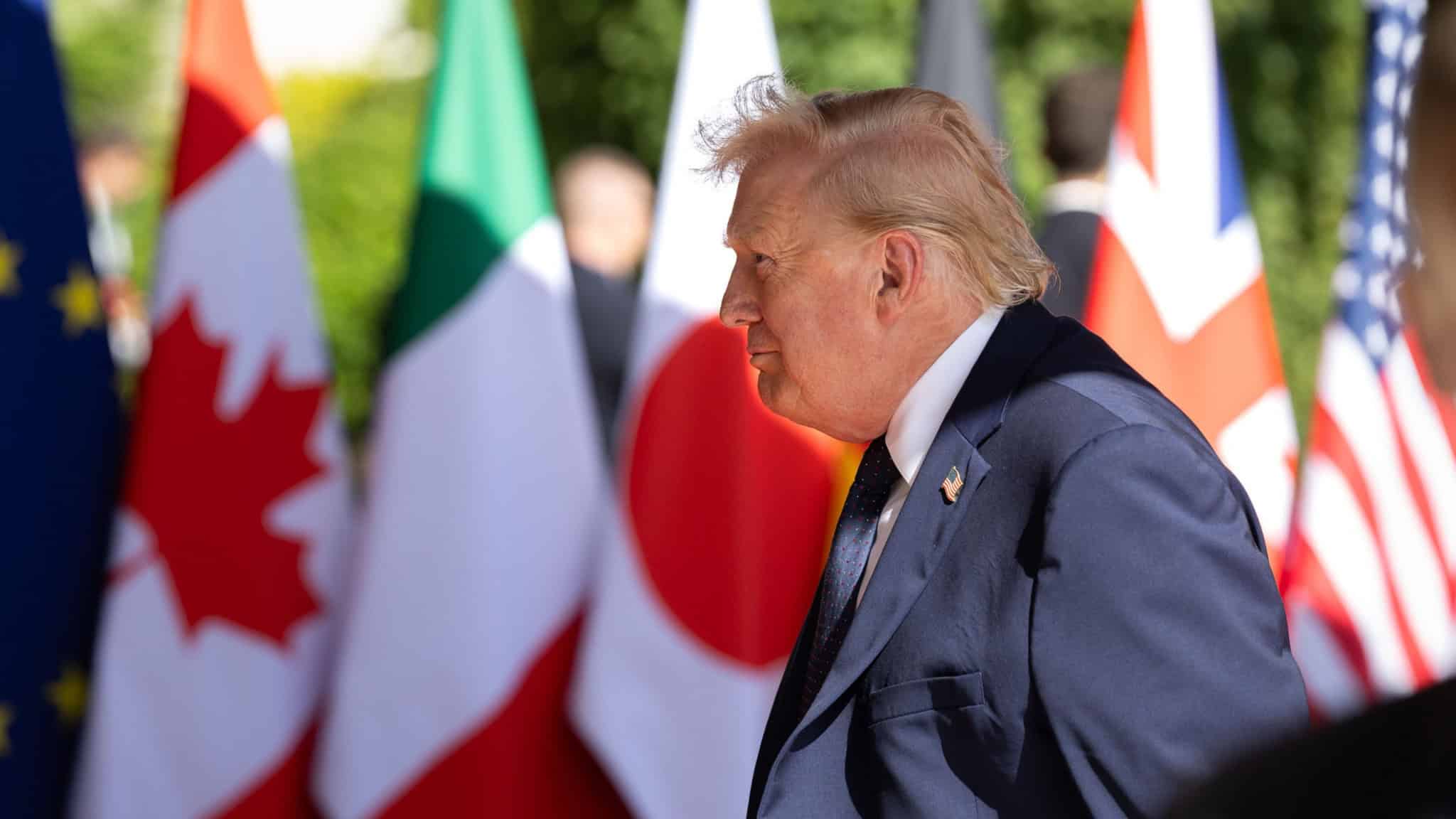 Donald Trump de lado; Trump está na frente de bandeiras de países, durante cúpula do G7, na França
